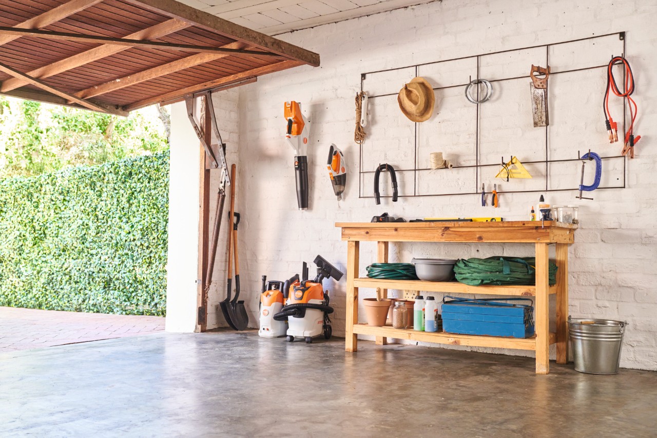 un garage avec un établi et des outils STIHL accrochés au mur
