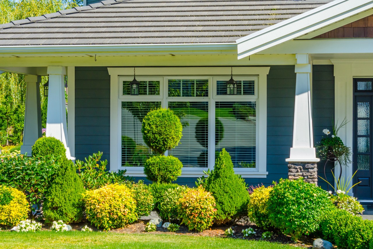 Jardin de façade joliment aménagé avec des plantes et des arbustes taillés