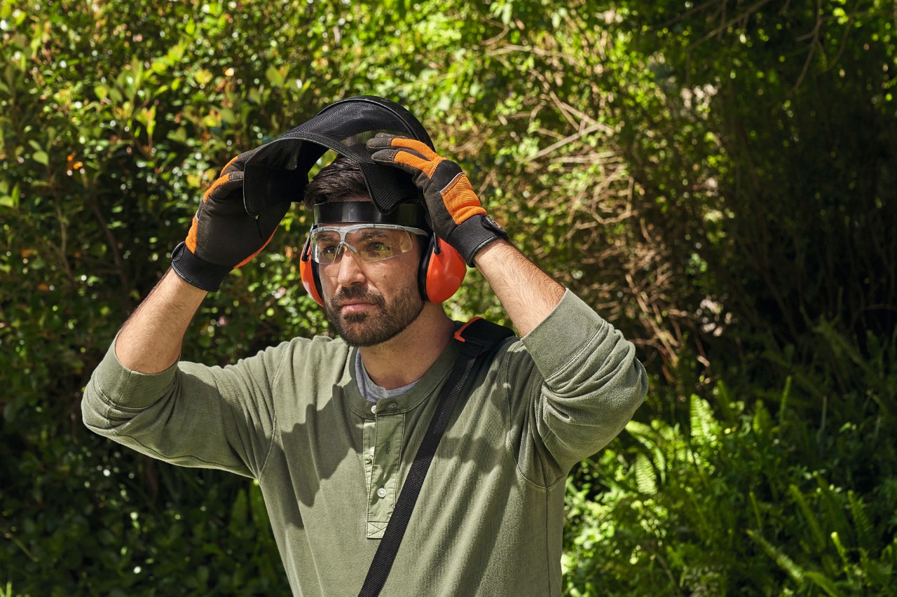 Un homme avec un équipement de sécurité STIHL dans un jardin 