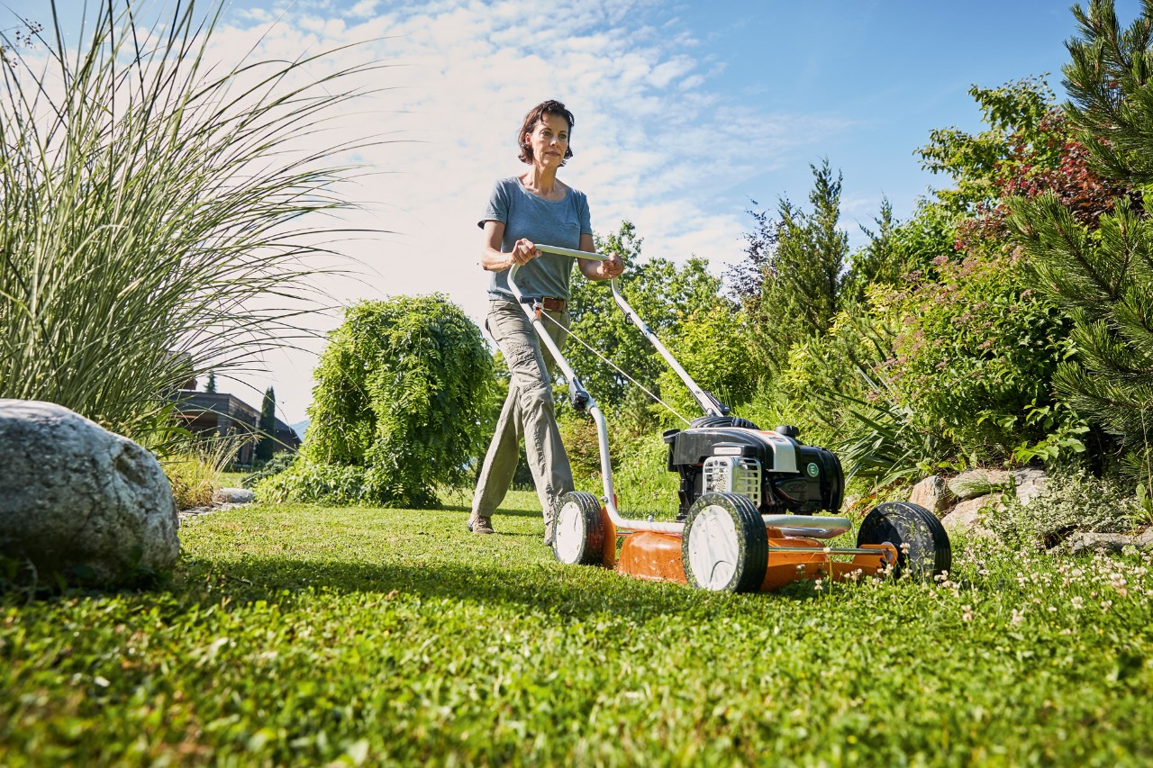 Femme réalisant le mulching avec une tondeuse à mulch à essence STIHL RM 2 R sur un terrain vert