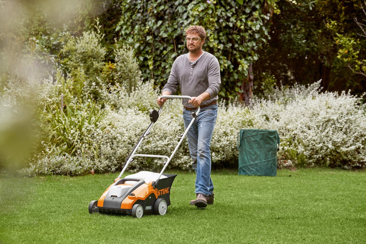 Un homme réalise le verticutage de pelouses vertes avec un scarificateur à batterie STIHL RLA 240