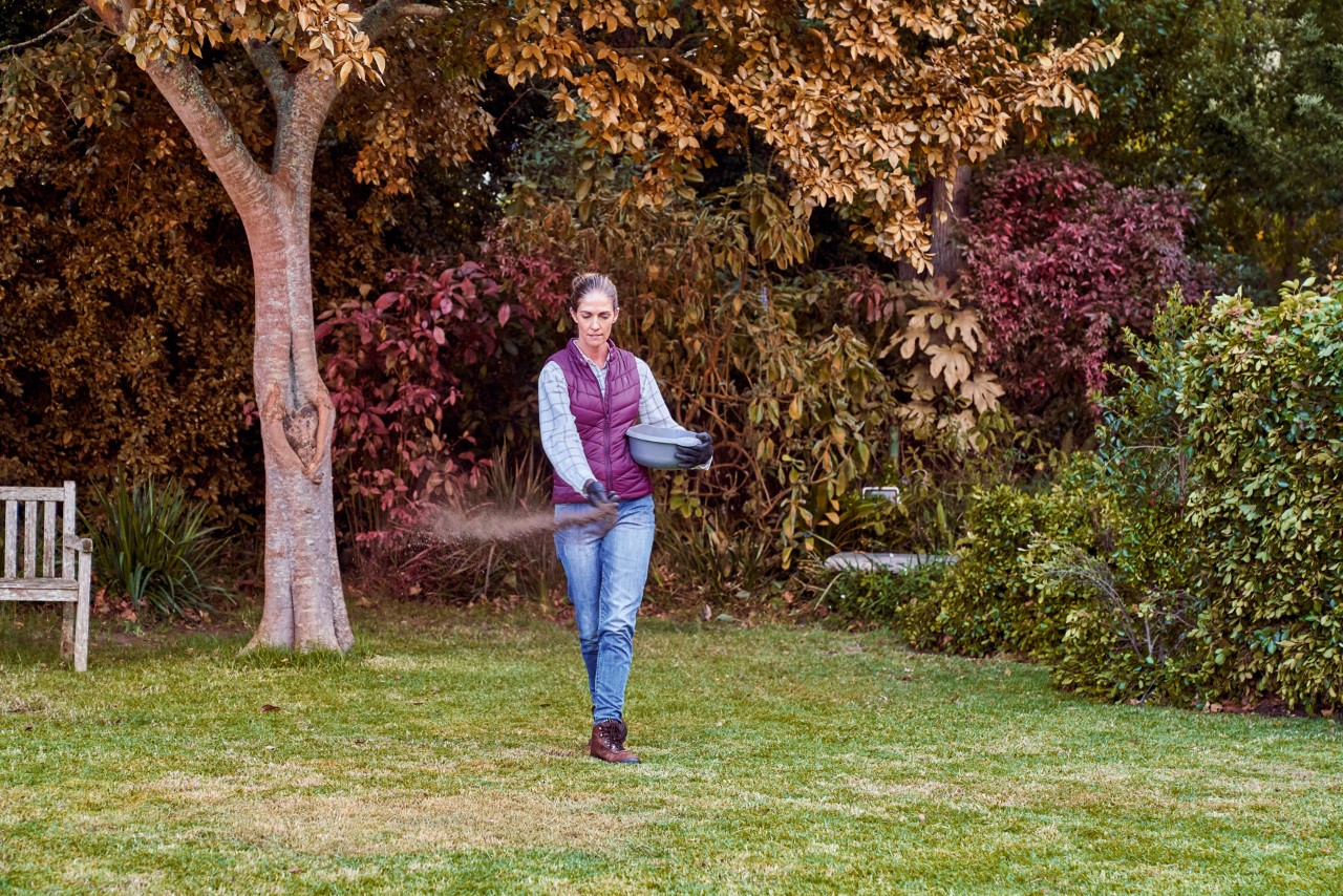 Une femme apporte de l’engrais dans son jardin