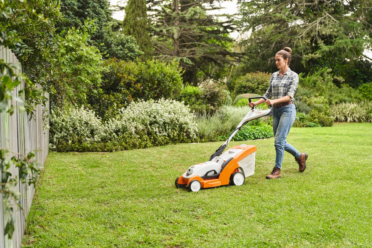 Une femme tond le gazon qu’elle a posé avec une tondeuse à gazon à batterie STIHL RMA 339&nbsp;C