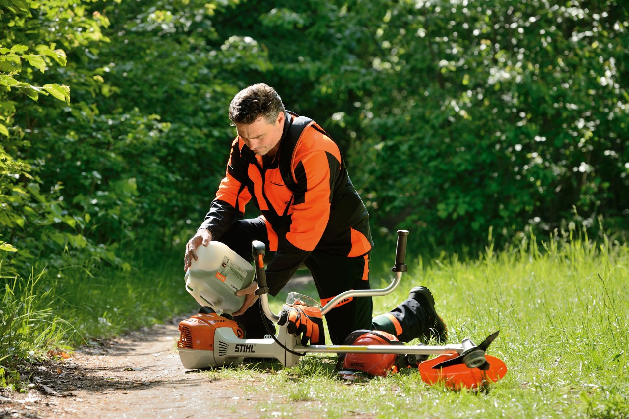 Homme faisant le plein de sa débroussailleuse STIHL avec un mélange essence/huile