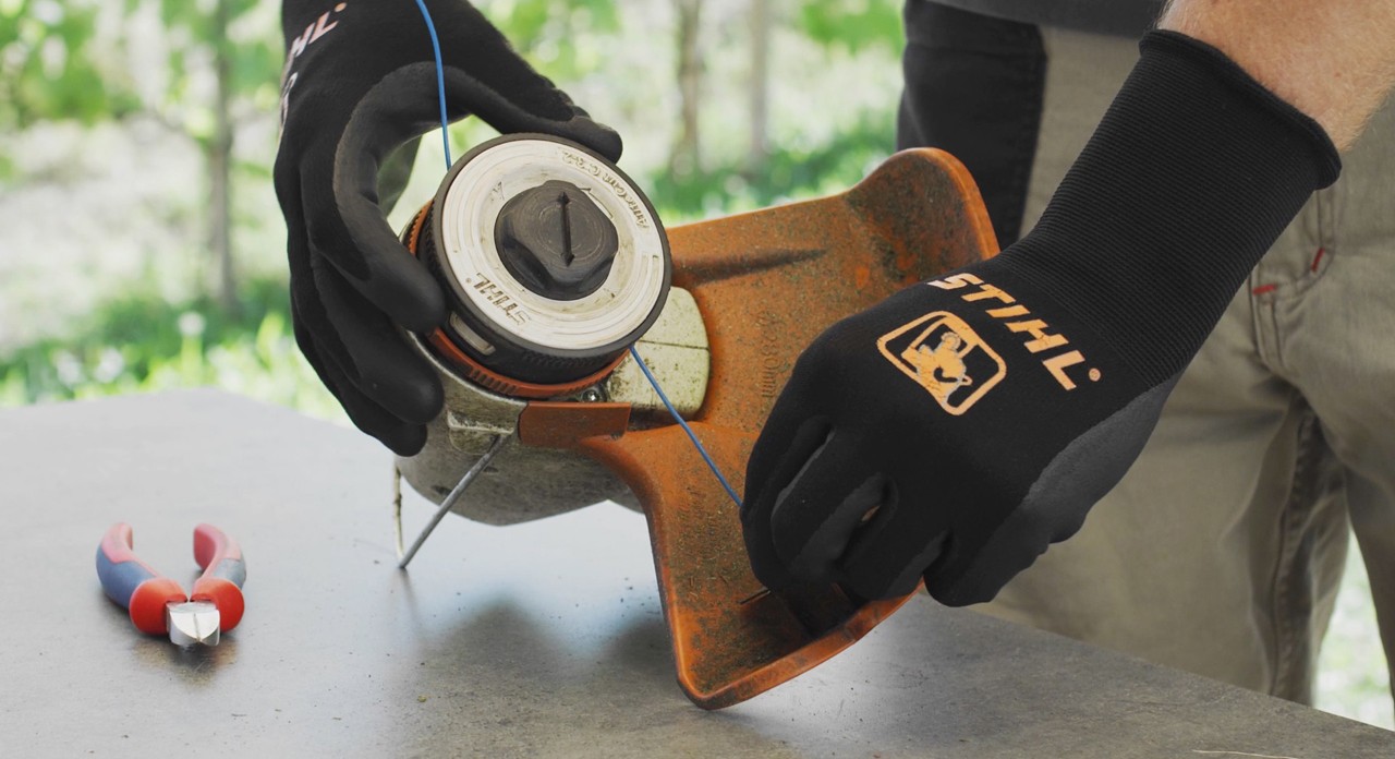 Une personne enroule le fil de coupe d’une débroussailleuse à batterie STIHL FSA&nbsp;57