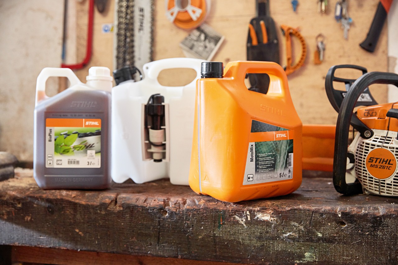 Bidon avec mélange d’huile et d’essence pour tronçonneuse STIHL MotoMix et tronçonneuse à essence STIHL MS&nbsp;261&nbsp;C dans un atelier