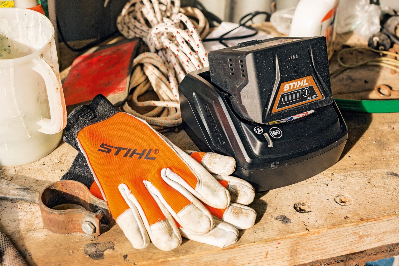Chargement de batteries lithium-ion de la série&nbsp;AK à côté de gants et d’outils de travail STIHL