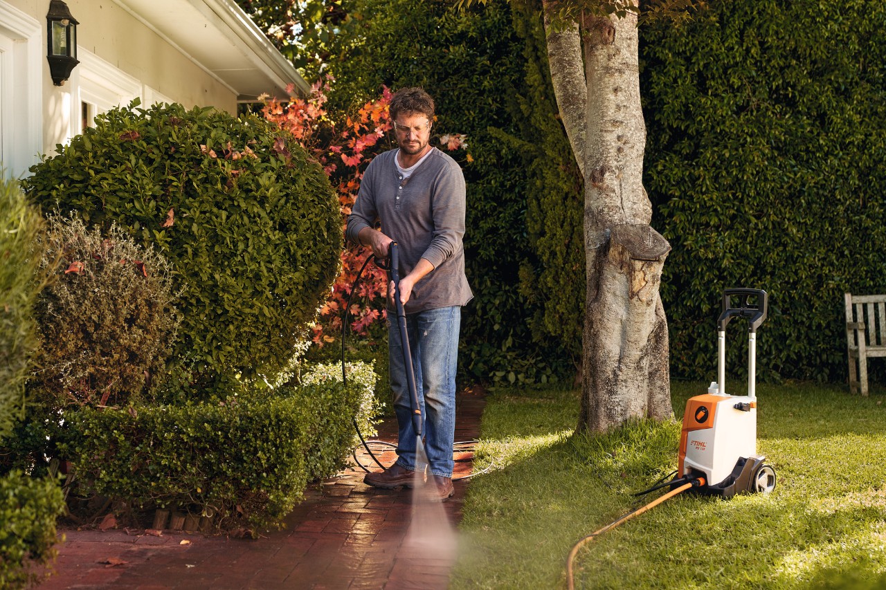 Un homme nettoie des pavés devant sa maison avec un nettoyeur haute pression STIHL RE 110
