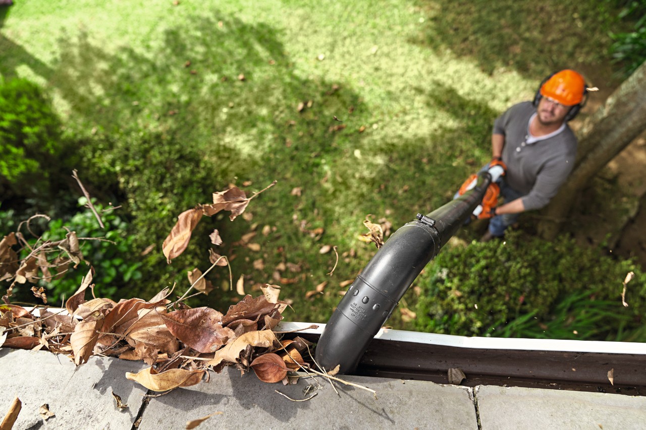 Un homme nettoie une gouttière avec le kit de nettoyage de gouttière STIHL