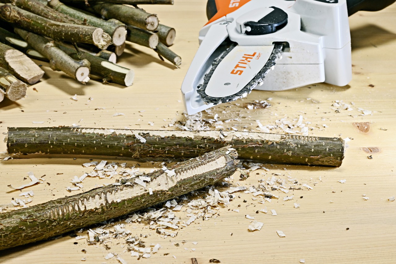 Lampe de salon DIY en brindilles : des branches aux reliefs rugueux devant une scie de jardin sur batterie STIHL GTA 26