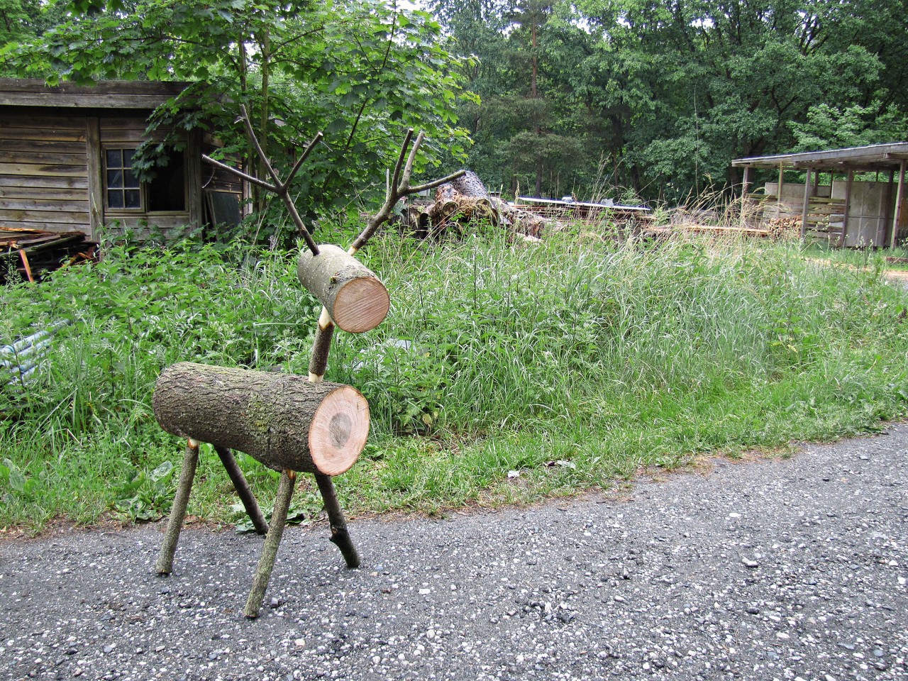 Renne en bois devant une pelouse verte et une cabane en bois