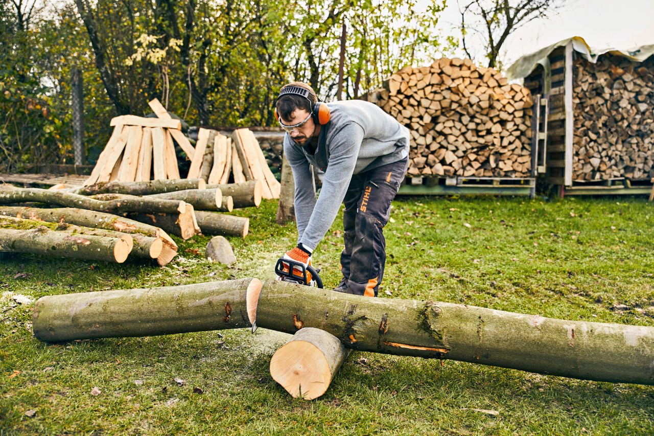 Un homme souhaite fabriquer soi-même une jardinière et scie pour cela un tronc d’arbre avec la tronçonneuse STIHL MS 180.