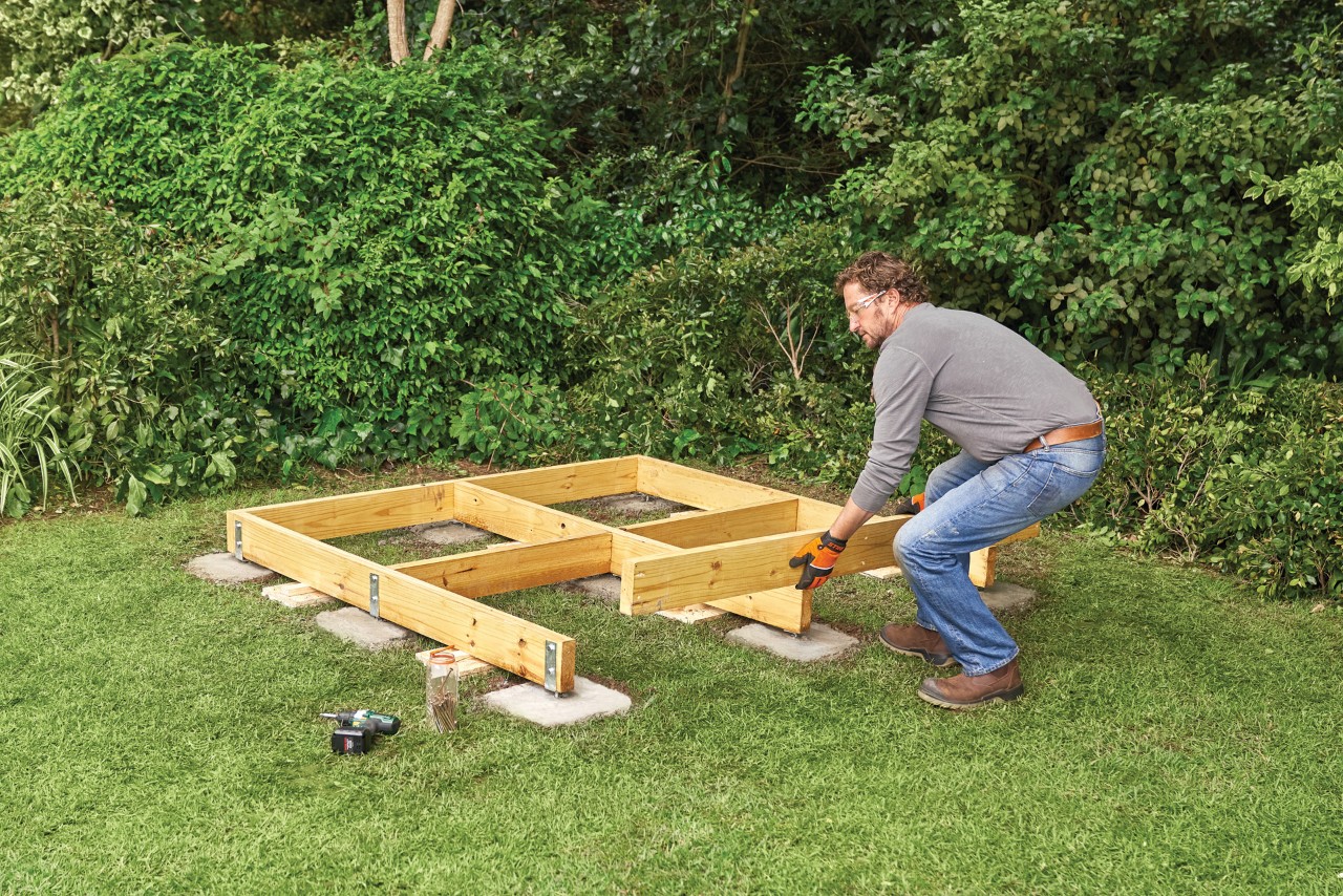 Comment construire un abri de jardin : homme construisant la base en bois d’un abri