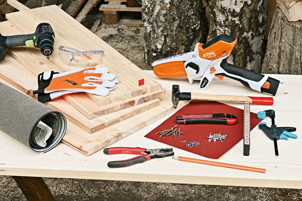 DIY abri pour hérisson - les matériaux et les outils : Une scie de jardin à batterie STIHL GTA 26, des planches en bois, un marteau, des clous et quelques autres outils