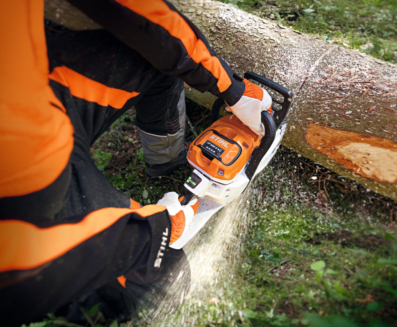 Gros plan sur une personne coupant un tronc d’arbre avec la tronçonneuse à batterie STIHL MSA 300