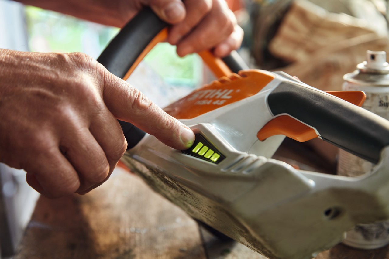 Une personne vérifie le niveau de charge du taille-haie sans fil STIHL HSA 45.