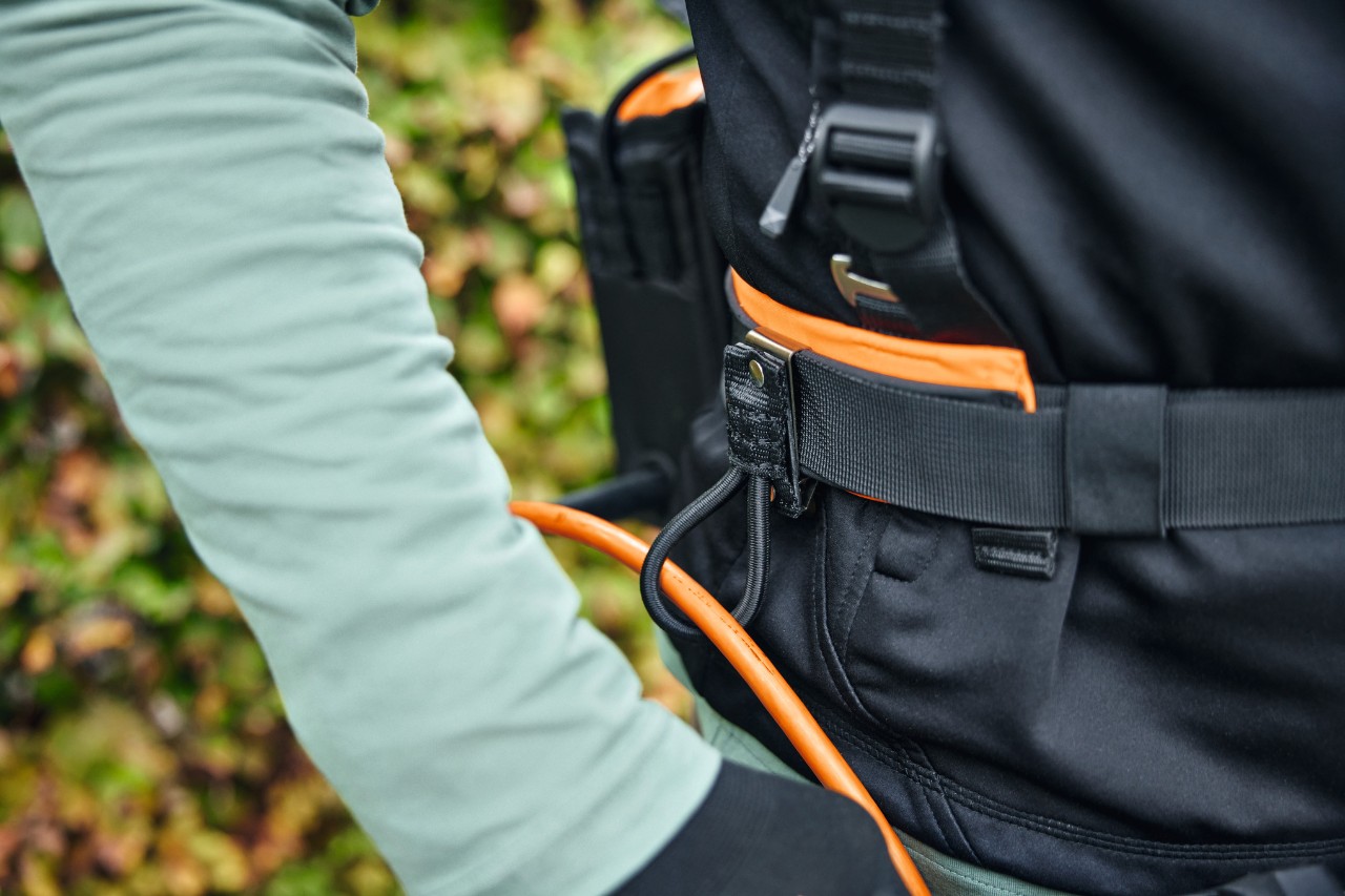 Personne portant le système de ceinture modulaire STIHL ADVANCE X-Flex avec une sacoche pour batterie avec câble de raccordement et guide-câble