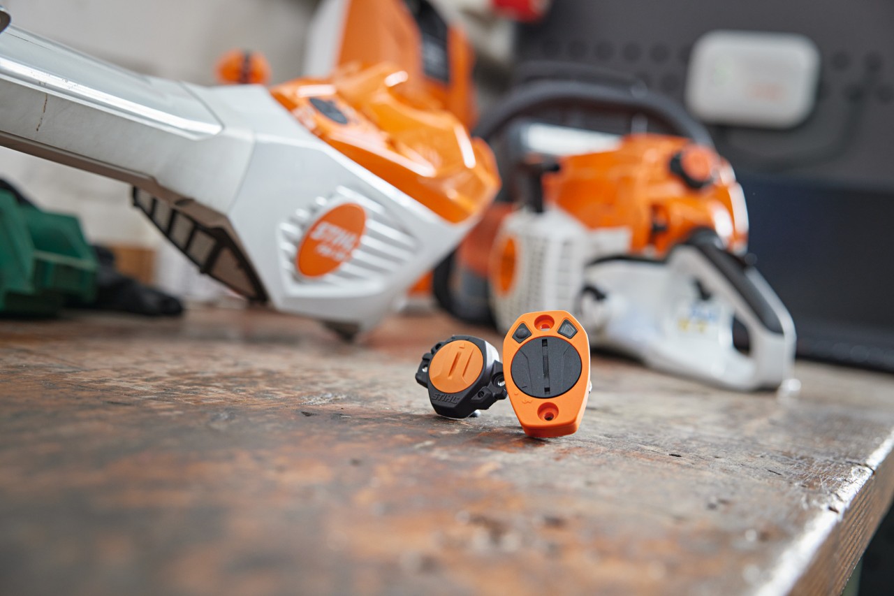 Appareils STIHL Smart Connector et Smart Connector A posés sur un établi. Différentes machines STIHL en arrière-plan.
