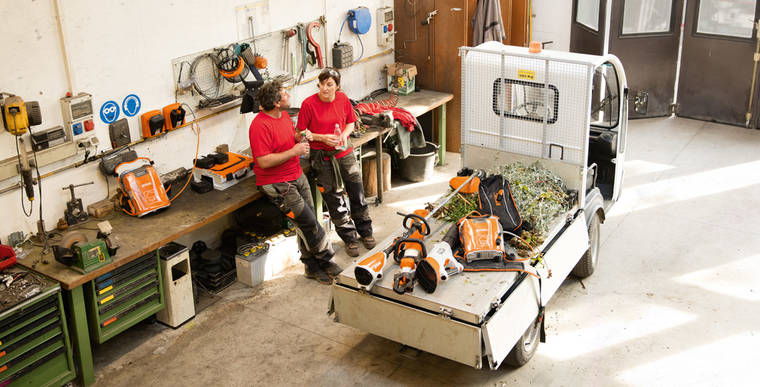 Un homme et une femme dans un atelier, entourés de machines STIHL et portant un pantalon de protection.